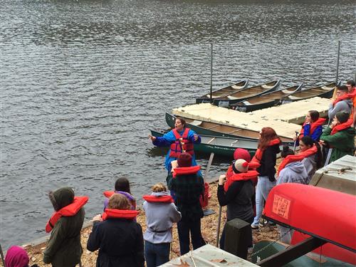 Students listening to instructions on how to use a canoe 